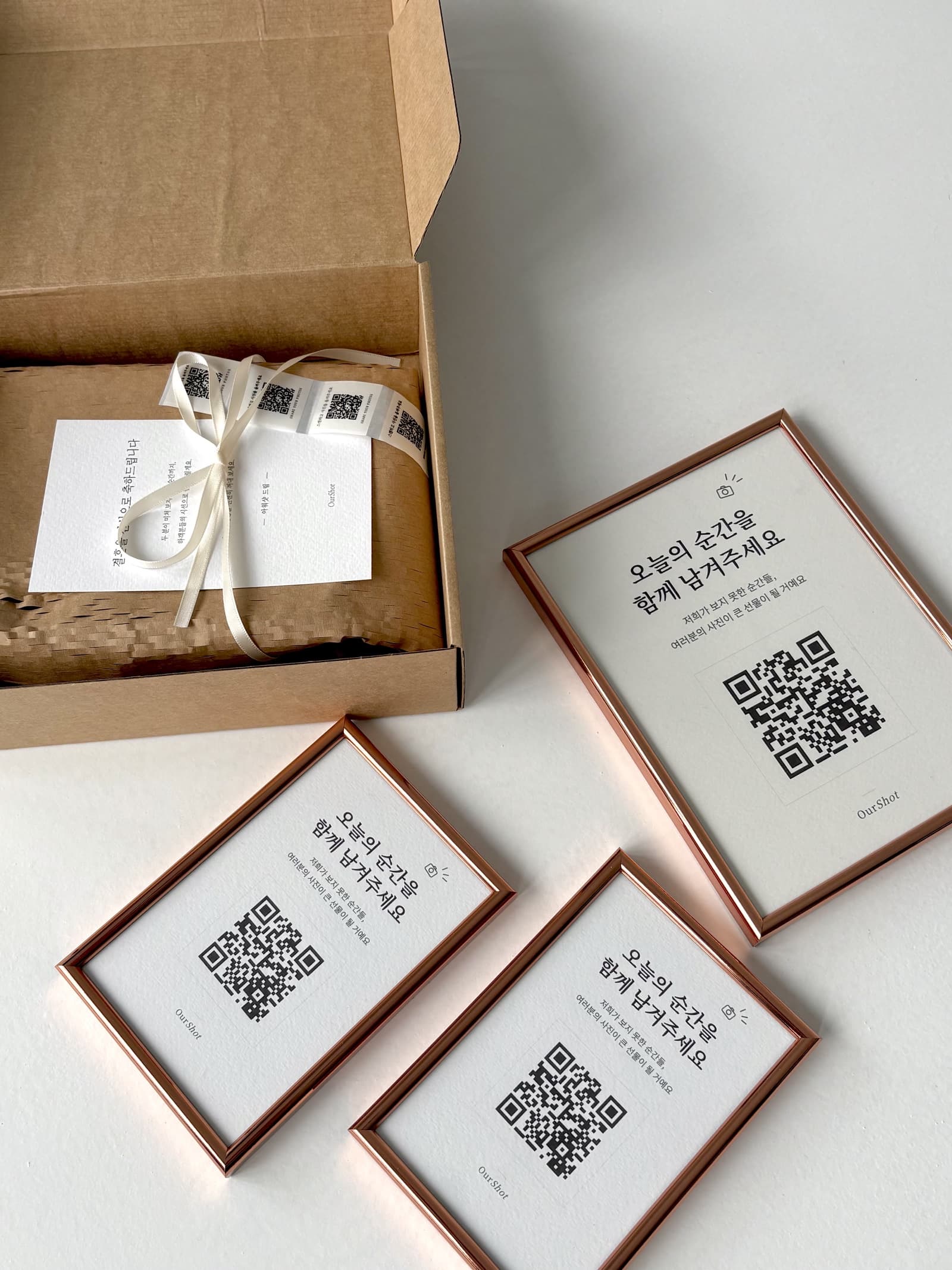 아워샷 QR 액자와 인쇄물이 패키지 주변에 놓인 모습